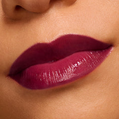 Close-up of glossy, plumped lips wearing Temptation, a deep berry shade of the ColourPop So Juicy Plumping Gloss, showing even coverage and a high-shine finish against bare skin.