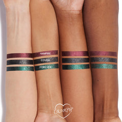ColourPop Graphix Ink Liner in Vampire swatched as a metallic burgundy stripe on three arms in light, medium, and deep tones, shown beside Coven (glittery black) and Forever (teal-green) for shade comparison; long-wearing, high-shine.