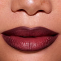 Close-up of a model’s lips wearing ColourPop New Love Lippie Stix, showing a smooth, deep berry-mauve Twilight inspired lip color with a soft satin finish against natural, freckled skin.