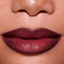 Close-up of a model’s lips wearing ColourPop New Love Lippie Stix, showing a smooth, deep berry-mauve Twilight inspired lip color with a soft satin finish against natural, freckled skin.