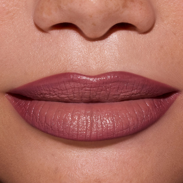 Close-up of full lips wearing ColourPop Opposites Attract Lippie Stix, showing a smooth, satin-matte mauve finish inspired by Twilight tones on medium skin, highlighting even coverage and creamy texture for everyday makeup looks.