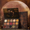ColourPop Twilight Forever palette trio New Moon edition opened to show 15 warm-toned shimmer and matte eyeshadows arranged in rows, set against a moody full-moon forest backdrop for Twilight makeup fans in the US.
