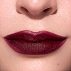 Closeup lips wear Newborn Powder To Creme Lipstick in a deep Twilight-inspired berry shade, showing smooth velvety texture and full coverage color against natural, softly lit skin.