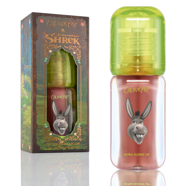 ColourPop Ultra Glossy Lip Noble Steed standing upright, showing mauve-pink gloss in a clear tube with neon green cap and Donkey graphic, positioned beside the ColourPop x DreamWorks Shrek forest-themed box.