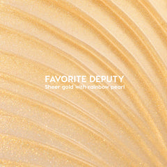 ColourPop Ultra Glossy Lip Favorite Deputy swatch sparkles in sheer gold with rainbow pearl; curved streaks fan across a glossy surface, showcasing a high-shine micro-glitter finish and lightweight, non-opaque coverage.