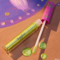 Pascal ColourPop Ultra Glossy Lip lying open with a doe-foot applicator and swirls of lime-green, gold-shimmer gloss, set on a Tangled-inspired painted backdrop, clear tube showing iridescent sheen and pink cap decorated with chameleon icons.