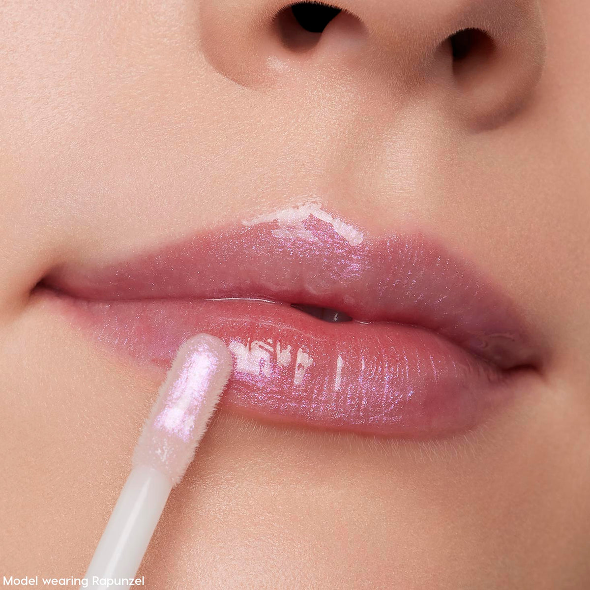Doe-foot applicator sweeping Rapunzel ColourPop Ultra Glossy Lip onto close-up lips, revealing a glassy, high-shine finish with sheer pink-lilac iridescent shimmer.