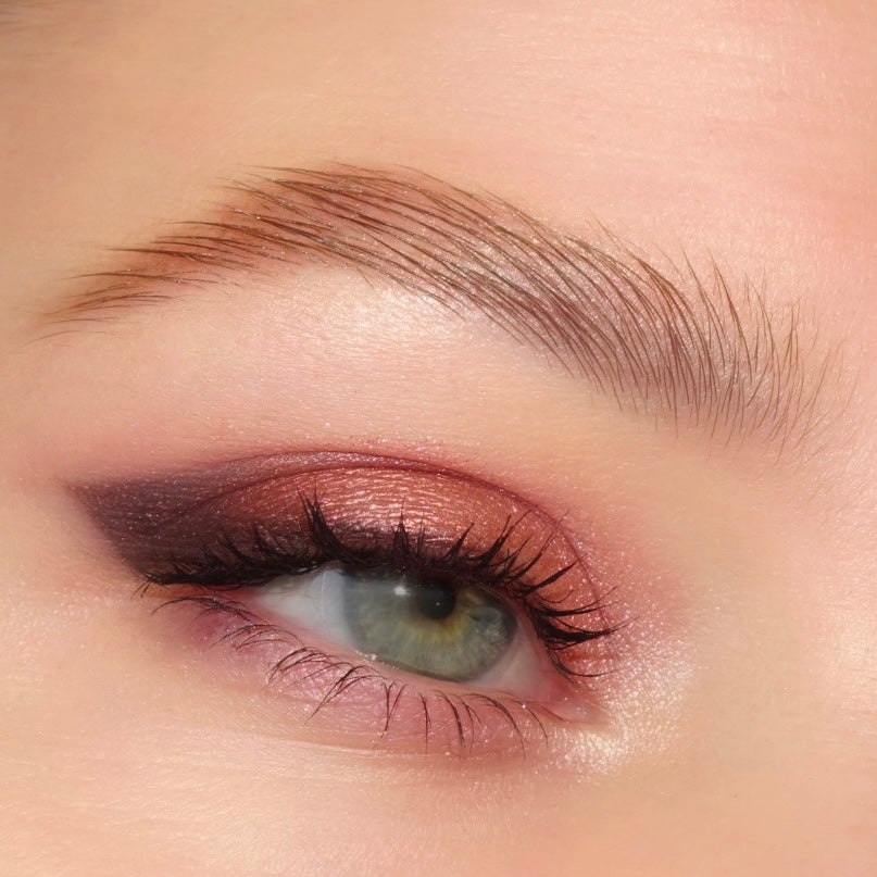 Green eye wears shimmering rose-copper shadow blended into a deep plum wing with defined lashes, showcasing Total Smokeshow, a ColourPop Shadow Palette & Brush Set, for a soft smoky cat-eye look.