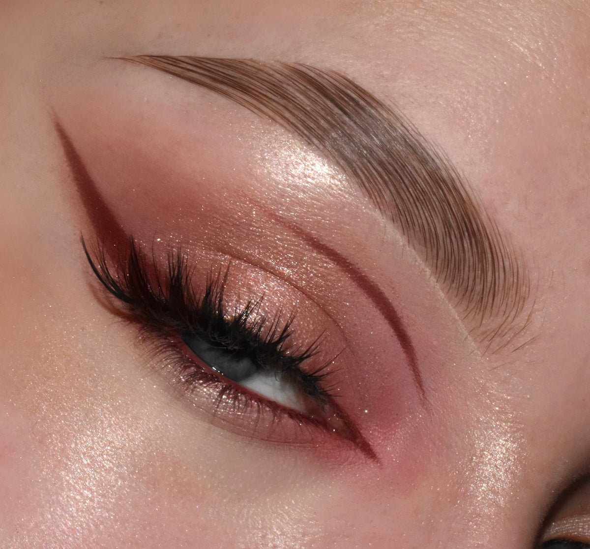Rose-gold glam eye showcases By The Rosé ColourPop Shadow Palette, shimmering pink lids blended with matte mauve and a deep wine cut-crease wing, finished with fluttery lashes and a highlighted brow in a studio close-up.