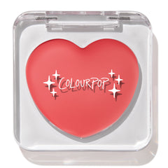 Heart-shaped ColourPop Lip and Cheek Balm in It’s a Look resting in a clear square compact with lid closed, showcasing a warm coral-pink shade and white ColourPop logo on a clean white background.