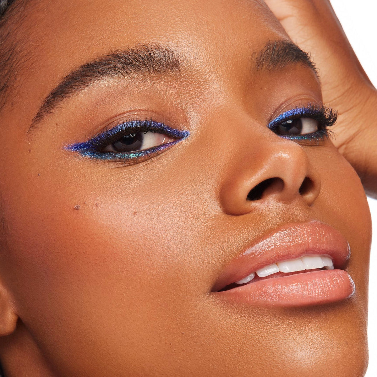 Ventura Blvd ColourPop Chrome Crème Gel Liner sweeping a bold cobalt-blue wing with a teal duochrome shift along upper and lower lash lines, shown in a close-up on a model with smooth skin and glossy nude lips against a bright studio backdrop.