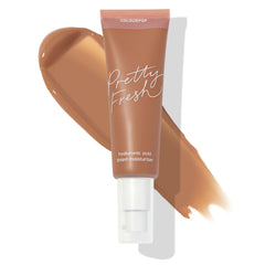 ColourPop Pretty Fresh Tinted Moisturizer in Medium Dark 16 N stands upright with a white pump and pink cap, labeled “hyaluronic acid,” set over a wide caramel-brown swatch that displays the neutral medium-dark shade on a white background.