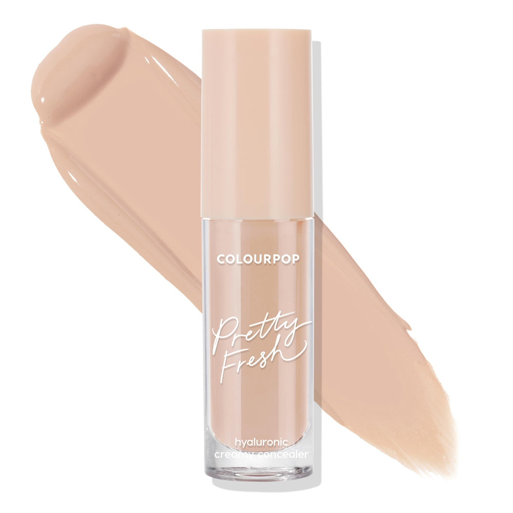 ColourPop Pretty Fresh Creamy Concealer, Light 60 N, stands upright in a clear tube with peach cap and white script, hyaluronic formula, shown with broad light neutral beige swatches behind on a white background.