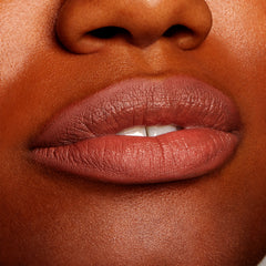 Full lips wearing All My BFFs, a warm rosy-brown nude ColourPop Lippie Pencil, lining and filling the mouth with a creamy satin finish on deep skin in a tight close-up, highlighting precise definition and smooth texture.