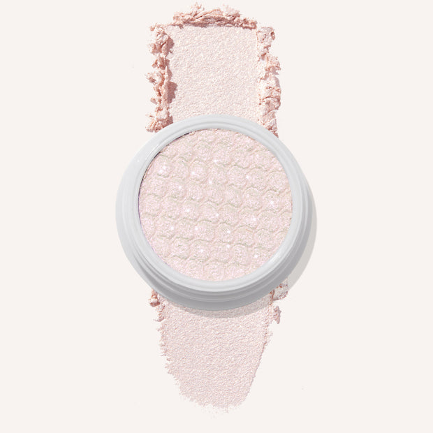 Colourpop Mountain Lion Super Shock Shadow single pan with a shimmery pale pink shade, showing its textured metallic finish and a soft swatch of the powder on a light background for detailed eyeshadow color payoff view.