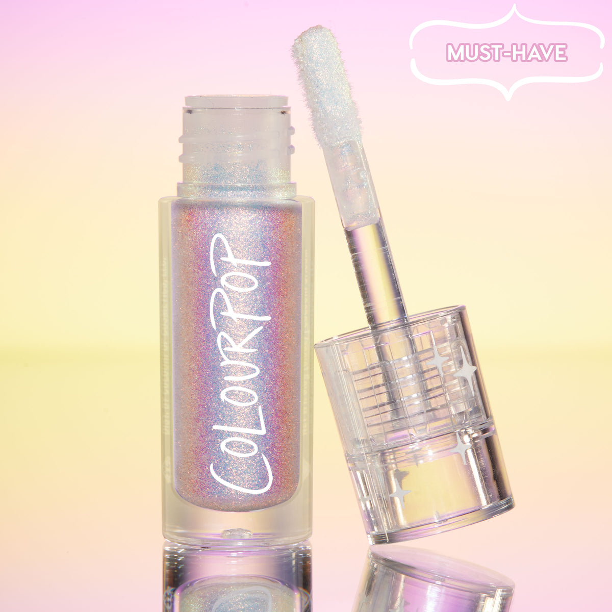 ColourPop Chrome Liquid Shadow in Glaze stands open, doe-foot applicator leaning on the iridescent tube, multichrome shimmer shifting pink, lilac, and blue, set on a pastel pink-to-yellow gradient with a “Must-Have” badge and mirrored surface.